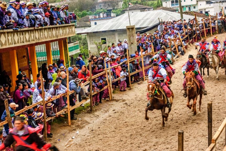Dirt arena in Todos los Santos Cuchumatán with wooden bleachers and crowds in traditional clothing during the ritual horse race ceremony in Guatemala'
