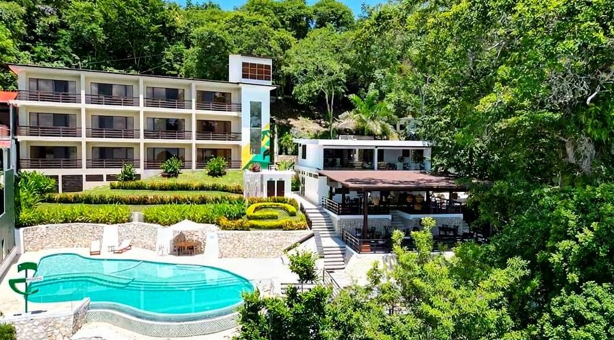 Modern boutique hotel on Petén Itzá with white architecture nestled in tropical jungle, turquoise pool and terraces overlooking Mayan forest