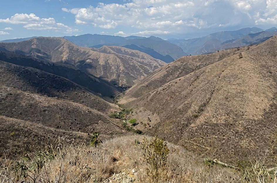 Rugged mountainous landscape of the Verapaces region showing arid brown peaks, sparse vegetation and lush green valley in Guatemala