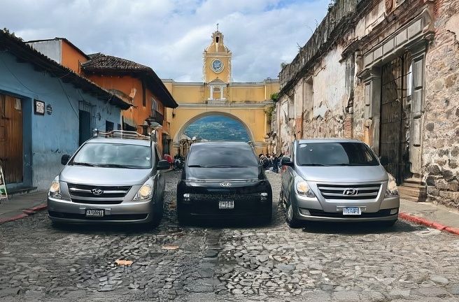 Colonial plaza in Antigua Guatemala with contrasting colored architecture and yellow-fronted church under cloudy sky