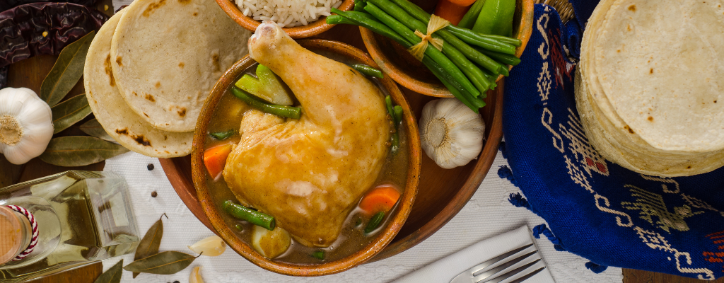 El pepián es un plato ancestral que tiene su origen en el departamento de Chimaltenango, al oeste de Guatemala. Muchas fuentes ubican el surgimiento de esta comida típica en la época precolombina, en donde era realizado por comunidades de etnia maya-kaqchikel que lo elaboraban para ceremonias importantes usualmente religiosos o políticos. Hoy en día el sabroso platillo ha evolucionado y se han creado varias versiones de este que son protagonistas de algunas de las festividades del país, e incluso fue declarado Patrimonio Cultural Intangible de la Nación en el 2007 por el Ministerio de Cultura y Deportes de Guatemala.

![blog-elaboracion-pepian.png](https://cdn.travelisimo.com/blog_elaboracion_pepian_2554f63666)

La salsa rojiza que caracteriza este plato es conocido tradicionalmente en el país como “recado”, que es un guiso o sopa espesa a base de vegetales y una amplia selección de especias, normalmente espesadas con pan, tortilla o masa cruda a base de maíz. Si no tuviste la oportunidad de probar este delicioso plato tradicional guatemalteco en tu viaje por el país, te compartimos la receta para que puedas elaborarlo y compartirlo con tu familia y amigos.

## Ingredientes
- 2 libras de carne (res, espinazo de cerdo o pollo entero trozado)
- 1 chile guaque seco (chule guajillo)
- 1 chile pasa seco (chile pasilla o poblano)
- 2 onzas de ajonjolí (sésamo)
- 1 raja de canela
- 2 onzas de pepitoria verde (semillas de calabaza)
- 4 pimientas gordas
- 4 tomates
- 1 chile pimiento
- 10 miltomates (tomate verde o tomatillo)
- 1 cebolla grande
- 3 dientes de ajo
- 1 manojo de cilantro
- ½ güisquil
- ½ libra de ejotes
- ½ libra de papas medianas
- 1 zanahoria grande
- 8 piezas de pan francés frío o 5 tortillas de maíz frías
- 1 litro de agua o caldo (de vegetales, pollo o res)

![blog-pepian-receta.png](https://cdn.travelisimo.com/blog_pepian_receta_be8251f520)

## Preparación
1. En una olla, colocar la carne y cocer con el litro de agua o caldo.
2. Agregar papa, güisquil, ejotes y zanahoria en trozos para que terminen su cocimiento junto con la carne.
3. En un comal o sartén, dorar los chiles, tomate, cebolla, miltomate, semillas y especias. 
4. Luego licuarlos con un poco del caldo de la carne y el pan ligeramente tostado.
5. Poner la mezcla a fuego medio y añadir el manojo de cilantro.
6. Dejar hervir el recado hasta que la mezcla esté espesa.
7. Agregar la carne y las verduras cocidas, se puede acompañar con arroz blanco y tortillas.

Ahora solo debes de disfrutar del delicioso pepián guatemalteco que preparaste.

---

No te pierdas la oportunidad de probar la comida típica de Guatemala y empieza a planificar tu viaje aquí.
## Travelisimo



