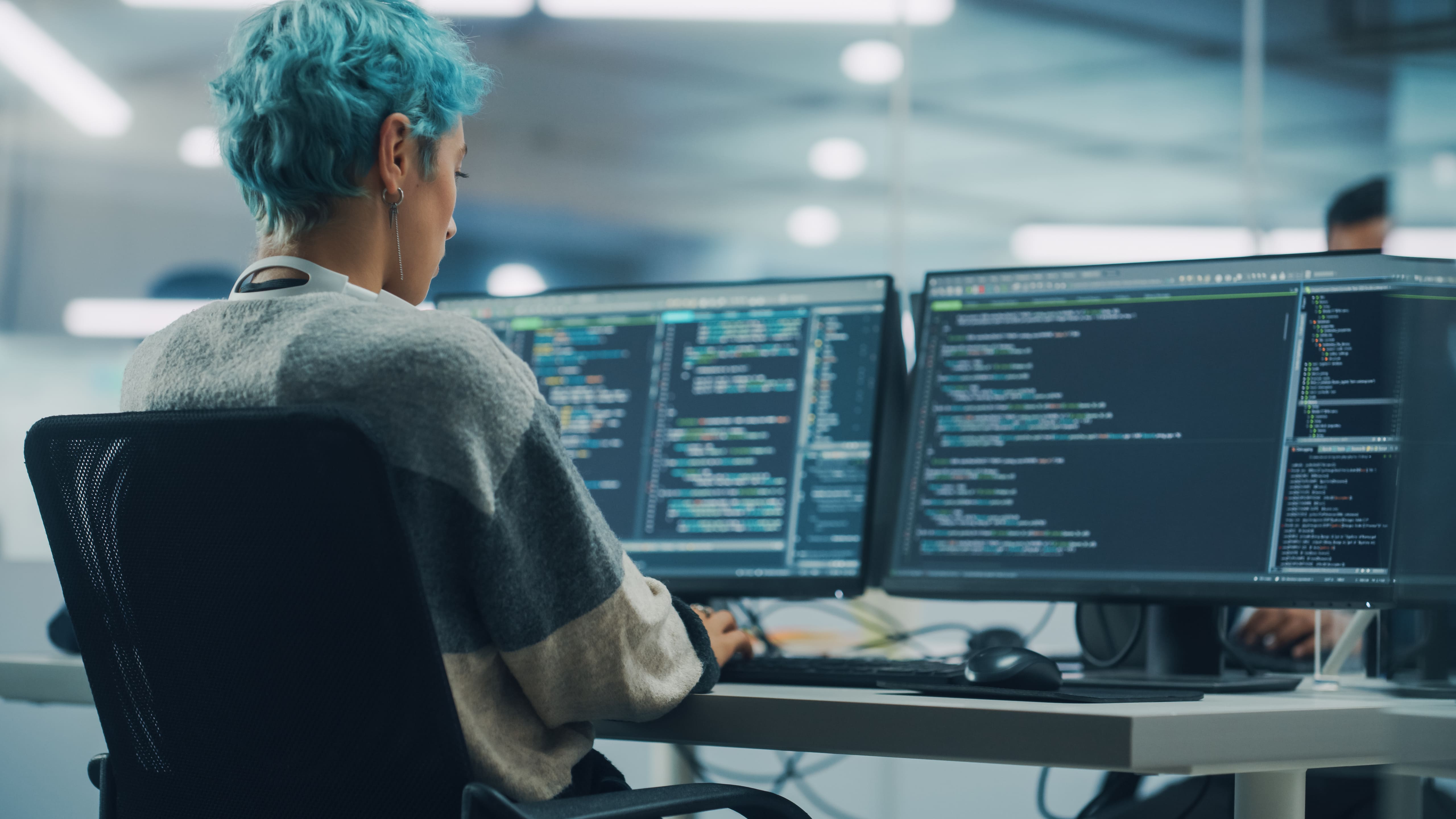 Woman facing computer and working on code